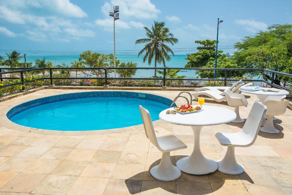 a patio with a table and chairs next to a pool at Golden Fortaleza by Intercity in Fortaleza
