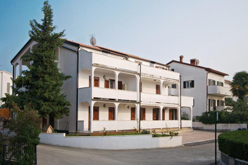 a large white building with a tree in front of it at Apartments AVA in Poreč