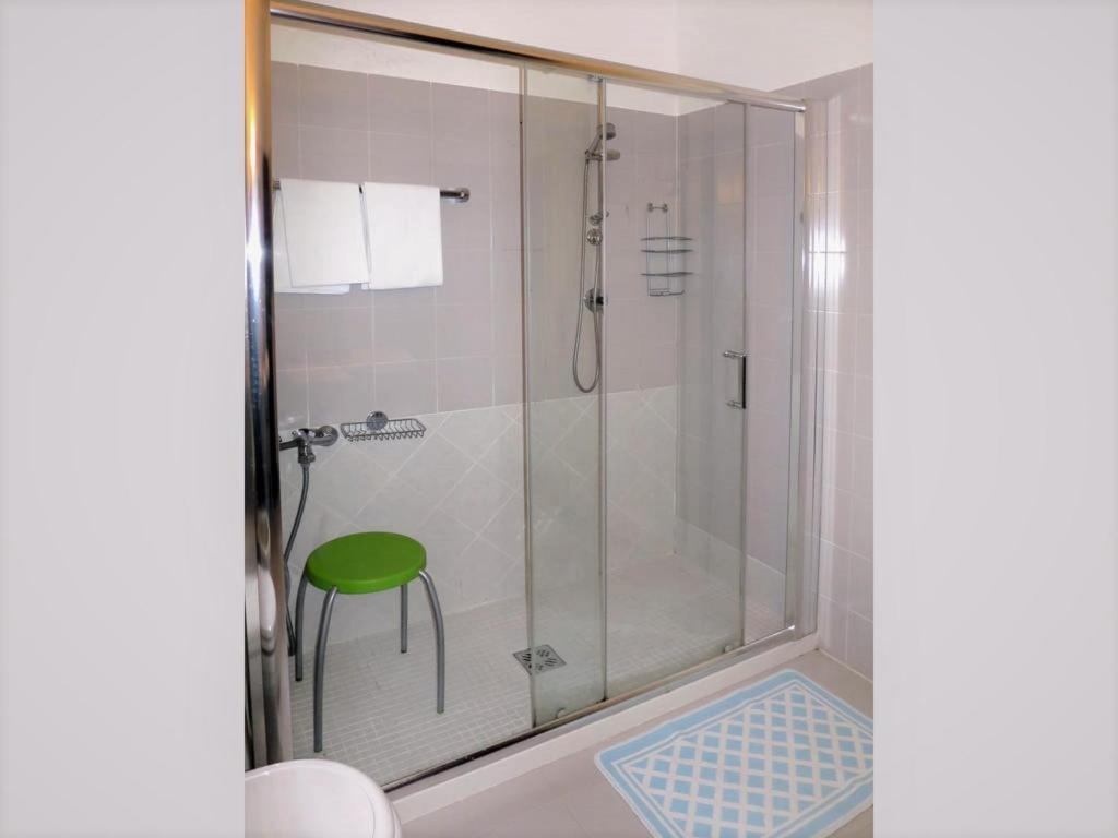 y baño con ducha y taburete verde. en Villa Margherita en Anduins