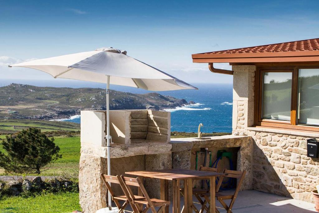 einen Tisch mit einem Regenschirm an der Seite eines Hauses in der Unterkunft Casa Cabo Tourinan in Queiroso