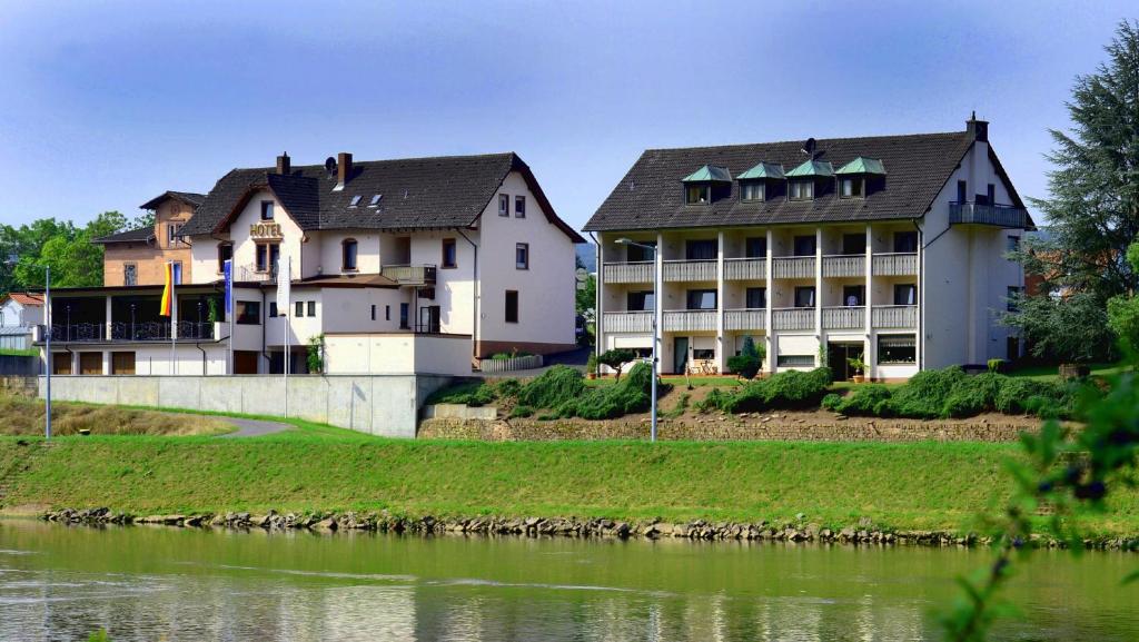 un groupe de bâtiments à côté d'une masse d'eau dans l'établissement Hotel Straubs Schöne Aussicht, à Klingenberg am Main