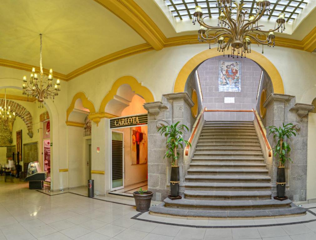 a staircase in a building with a chandelier at Hotel La Alhondiga in Puebla