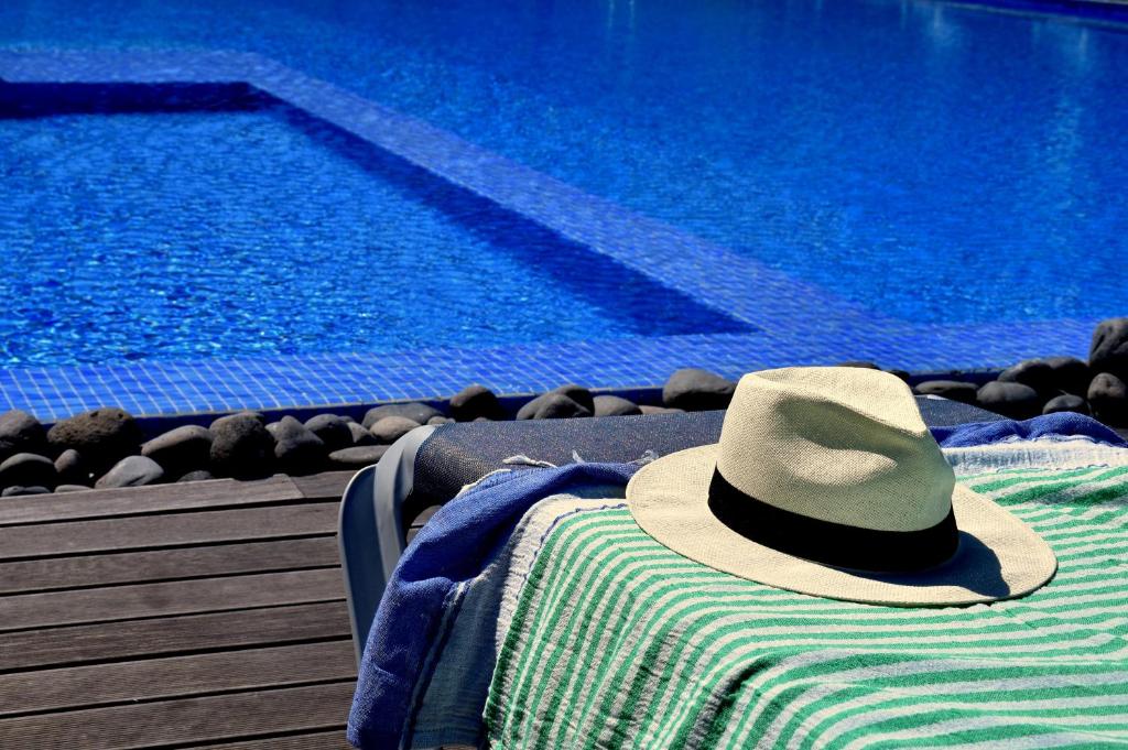 a hat sitting on a towel next to a swimming pool at Cantinho da quinta in Funchal