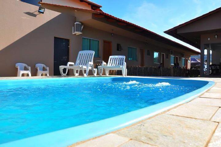 uma piscina com cadeiras e uma casa em Pousada Canto Dos Passaros em Pirenópolis