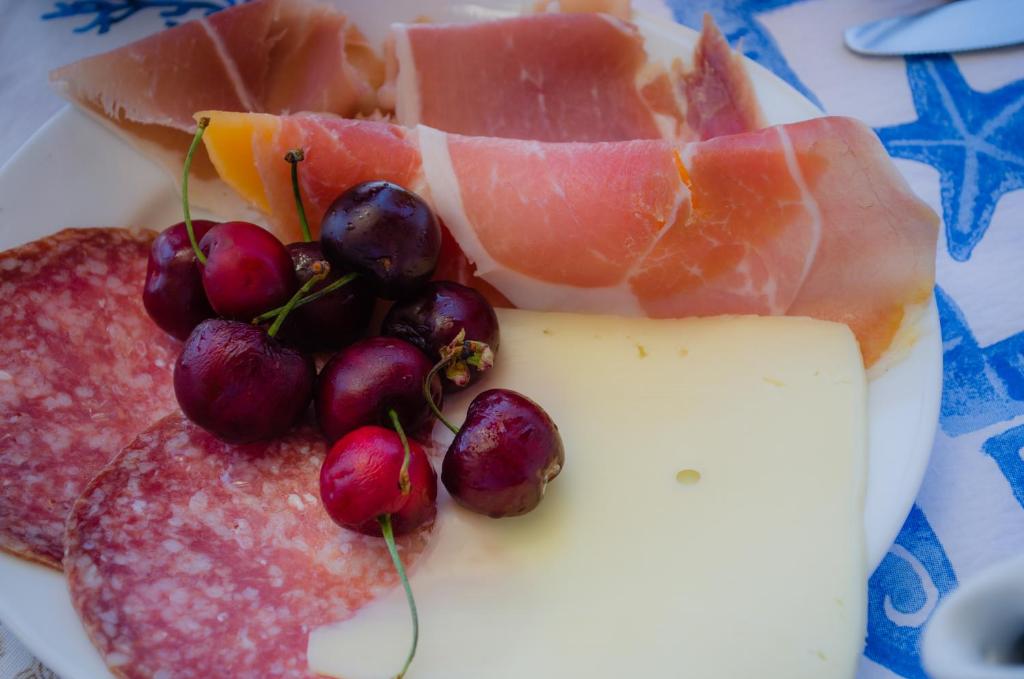 a plate of food with meat grapes and cheese at Hotel Angelino in Ischia