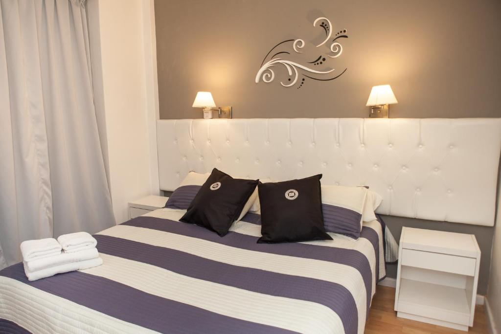 um quarto com 2 camas com almofadas pretas e brancas em Dodo Suites em Mar del Plata