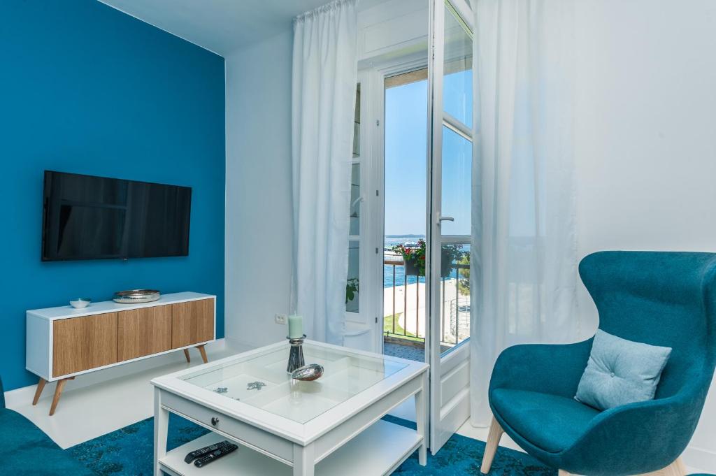 a blue living room with a blue chair and a tv at Aquamarine Sea View Apartment in Zadar