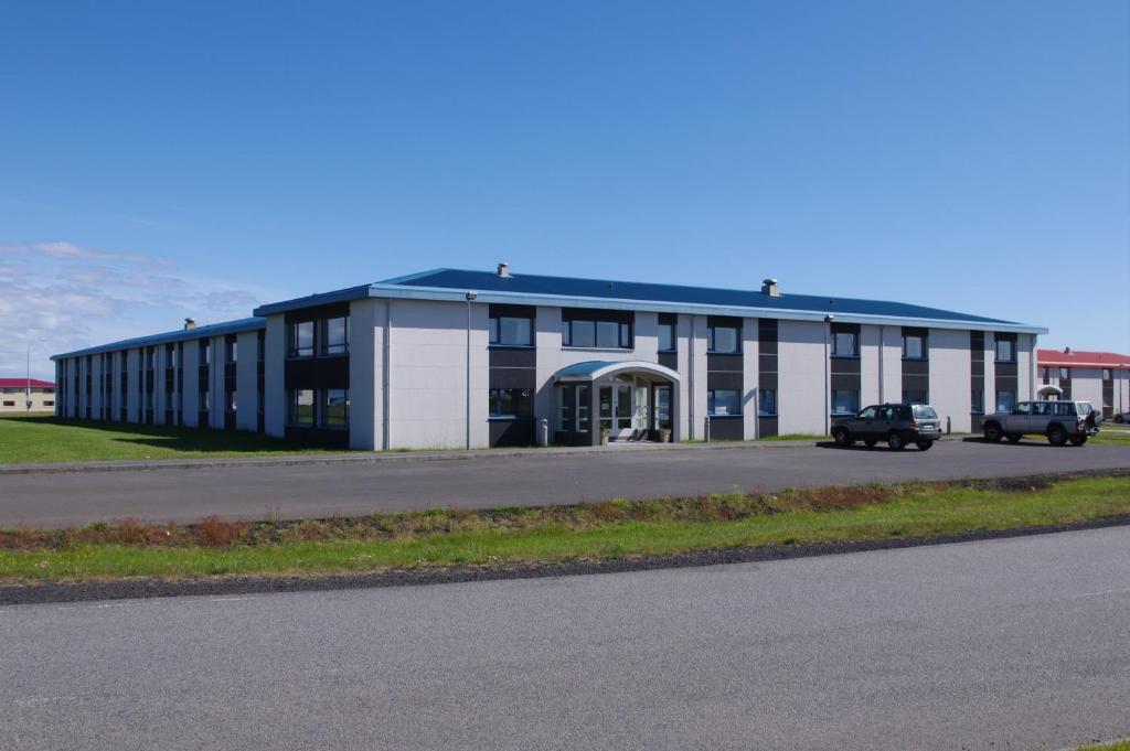 un grand bâtiment blanc avec des voitures garées devant lui dans l'établissement Start Keflavík Airport, à Keflavík