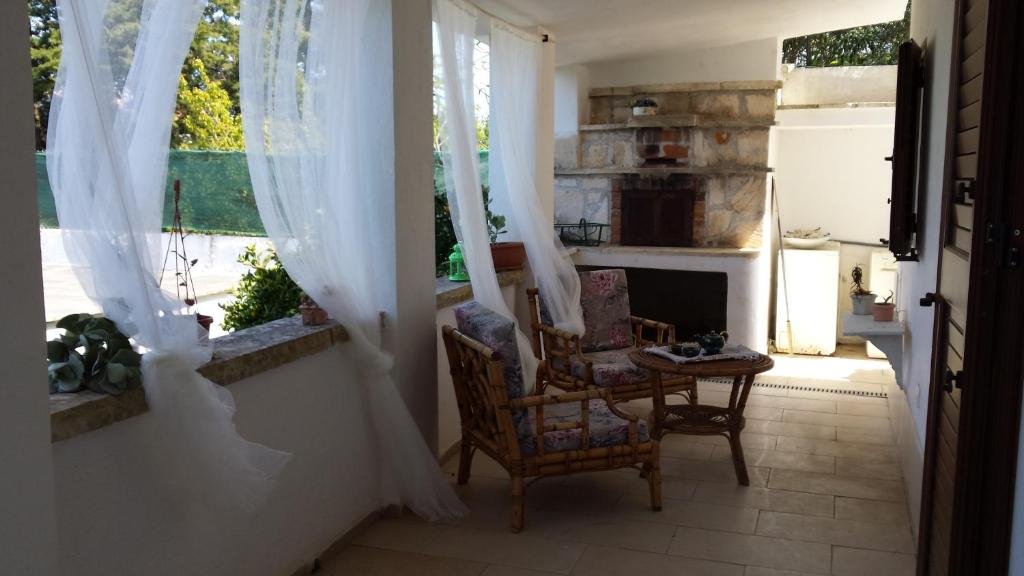 um quarto com duas cadeiras e uma lareira com cortinas em Villa Gardenia em Ostuni