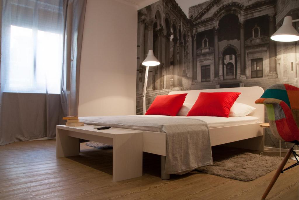 a bedroom with a white bed with red pillows at Bonum Rooms in Split