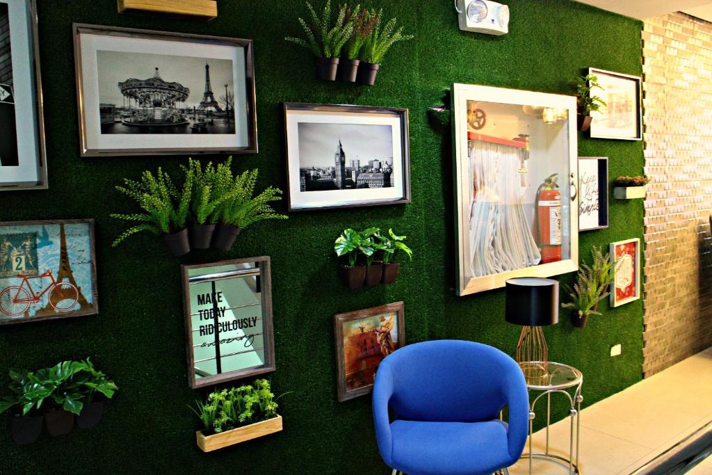 a green wall with pictures and a blue chair on it at Food District Hostel - Ortigas Kapitolyo in Manila