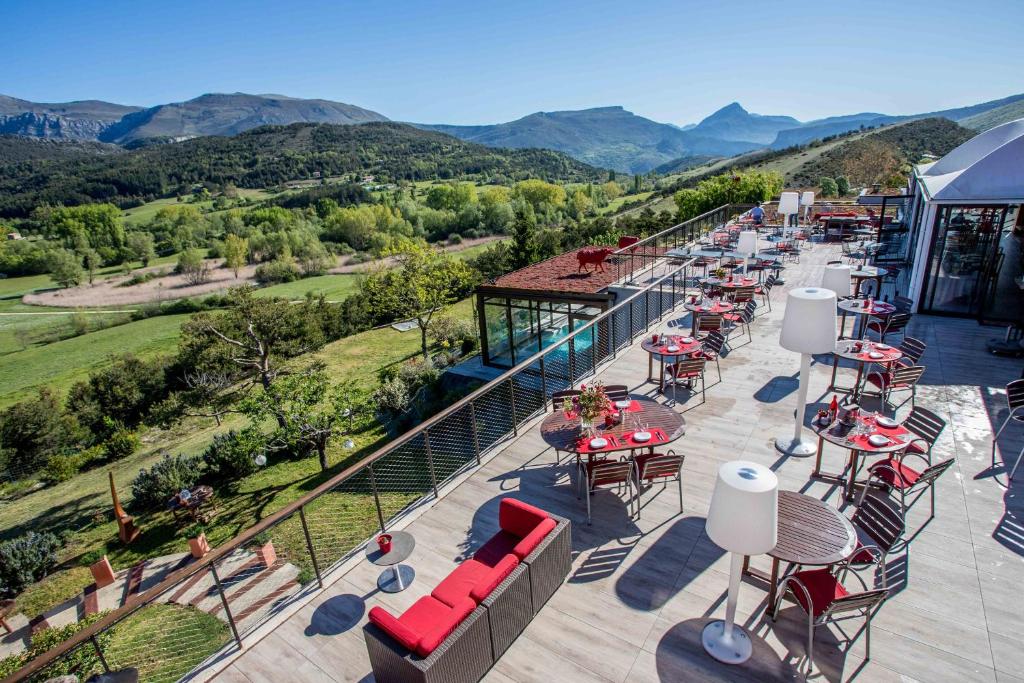 un patio esterno con tavoli, sedie e montagne di Hotel & Spa des Gorges du Verdon a La Palud-sur-Verdon