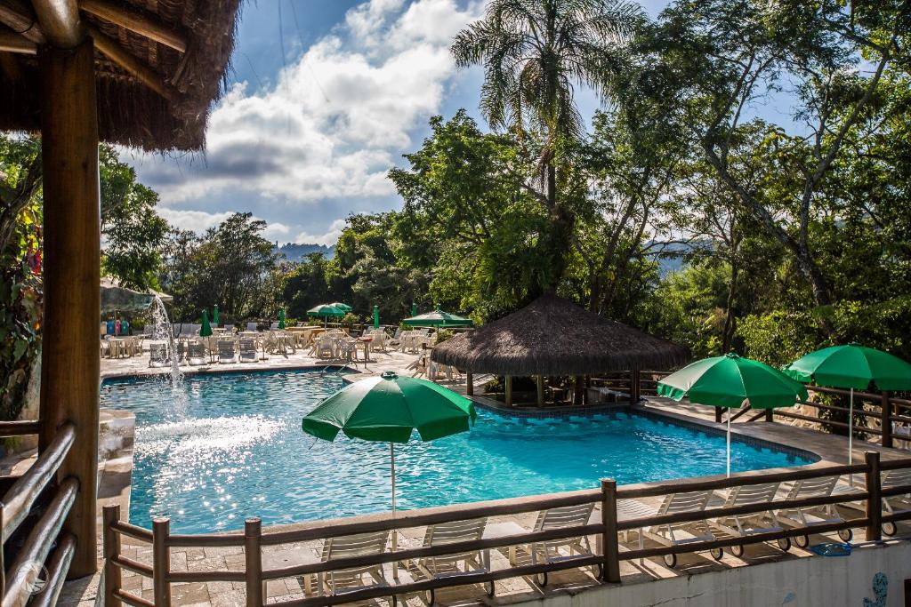 a large swimming pool with green umbrellas and chairs at Ecoresort Refúgio Cheiro de Mato in Mairiporã