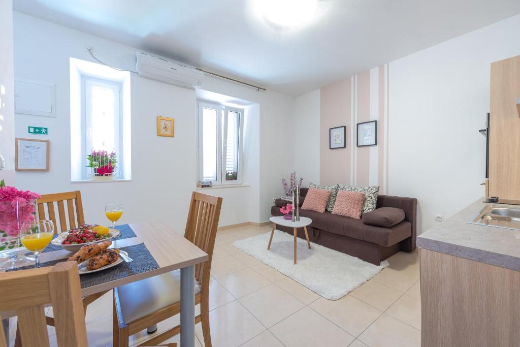 a kitchen and living room with a table and a couch at Fora Apartments in Dubrovnik