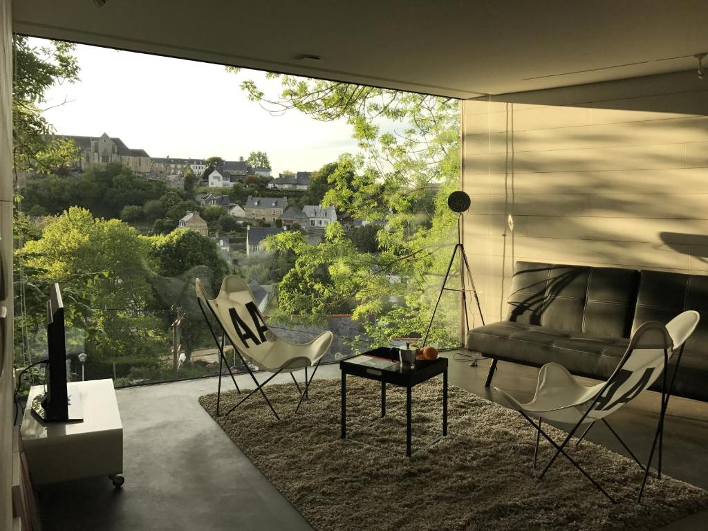 a living room with a couch and chairs in front of a window at Le studio Florent in Lannion