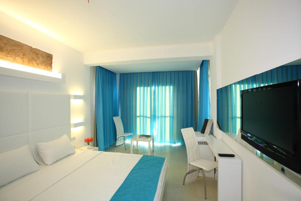 a hotel room with a bed and a flat screen tv at Costa Luvi Hotel Bodrum - All Inclusive in Gümbet