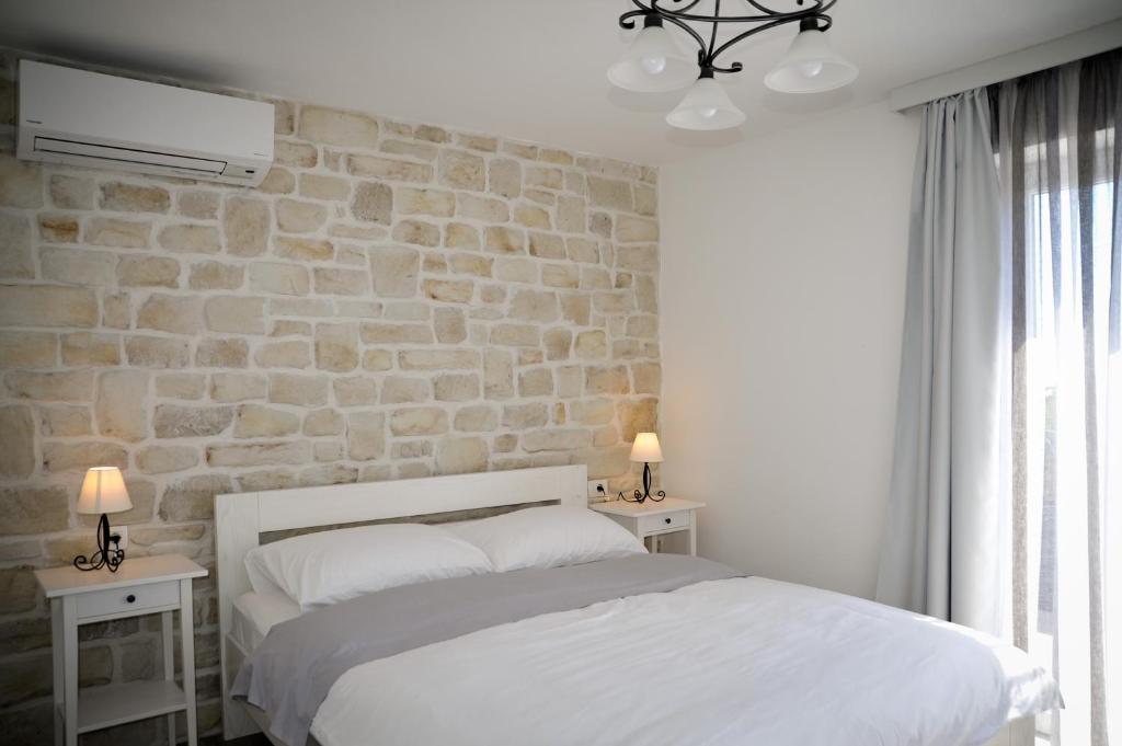 a bedroom with a white bed and a stone wall at APP Rab Banjol 217 in Banjol