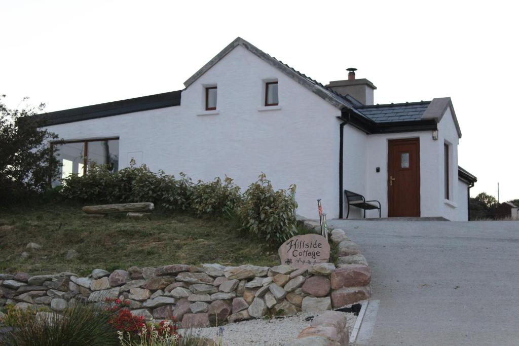 a white house with a sign in front of it at Hillside Cottage Achill in Achill Sound