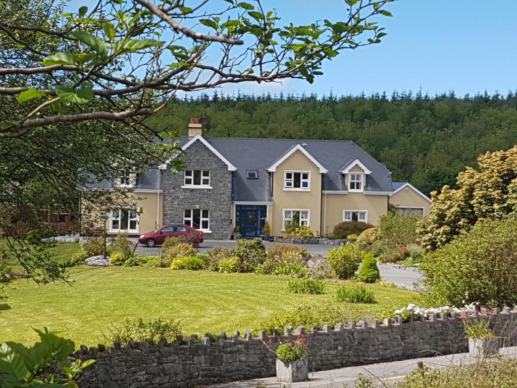 uma casa grande com uma parede de pedra em Greenlawn Lodge em Lisdoonvarna