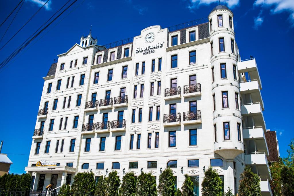 a white building with a clock on it at Sobranie hotel in Volgograd