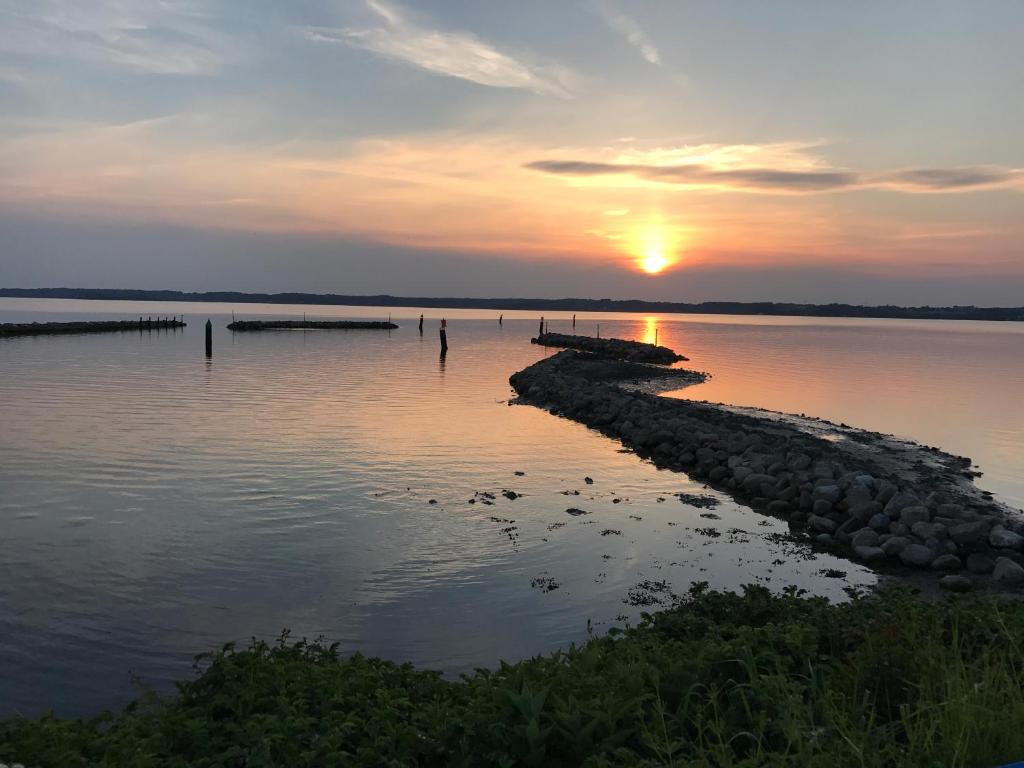 einen Sonnenuntergang über einem Wasserkörper mit einem Pier in der Unterkunft Meerblickappartement in Glücksburg