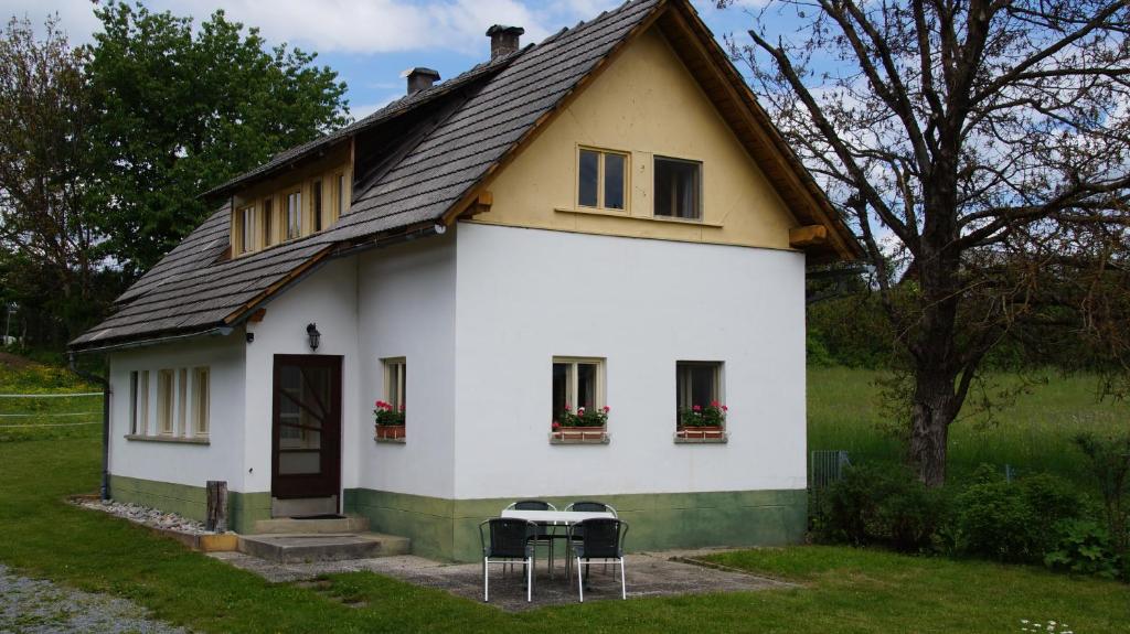 una casa blanca con tres sillas delante en Ferienhaus Dobernigg, en Sankt Jakob im Rosental