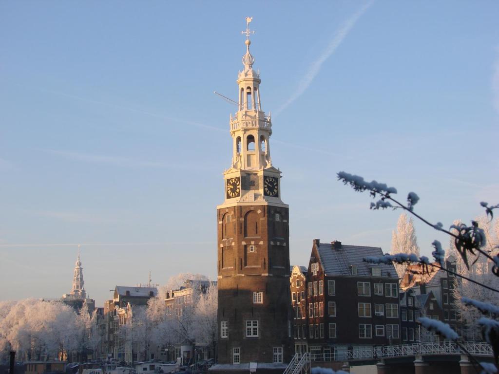 un edificio alto con una torre de reloj en una ciudad en Kalkmarkt Suites, en Ámsterdam