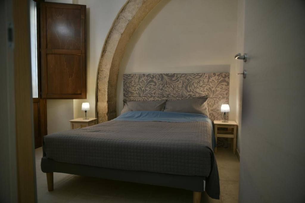 ein Schlafzimmer mit einem Bett und zwei Tischen mit Lampen in der Unterkunft Il Vinile Apartment in Syrakus