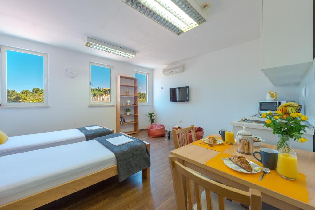 1 dormitorio con cama, mesa y cocina en Studio apartment Ivona, en Dubrovnik