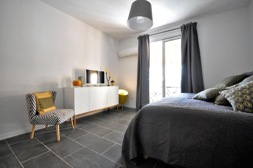 une chambre avec un lit, une télévision et une chaise dans l'établissement Appartement des fleurs, à Nice