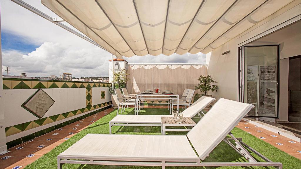 a patio with white chairs and a table on a roof at Beach Penthouse in Sitges