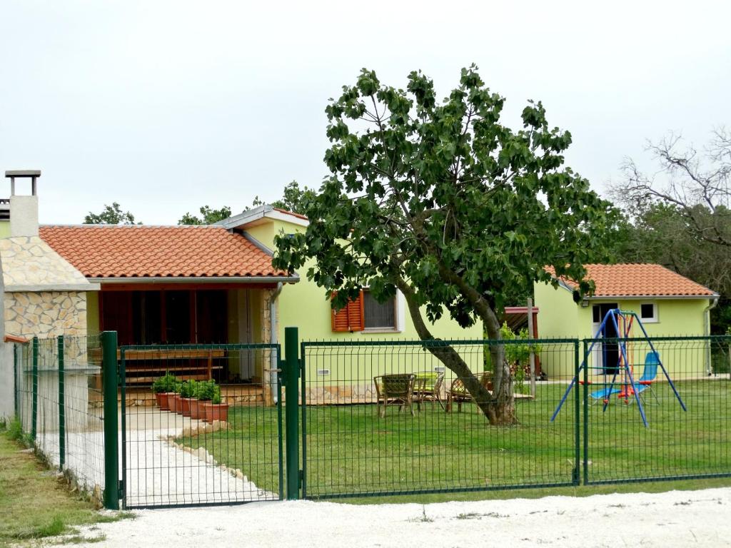 une clôture en face d'une maison avec une aire de jeux dans l'établissement Kuća Renata, à Pula