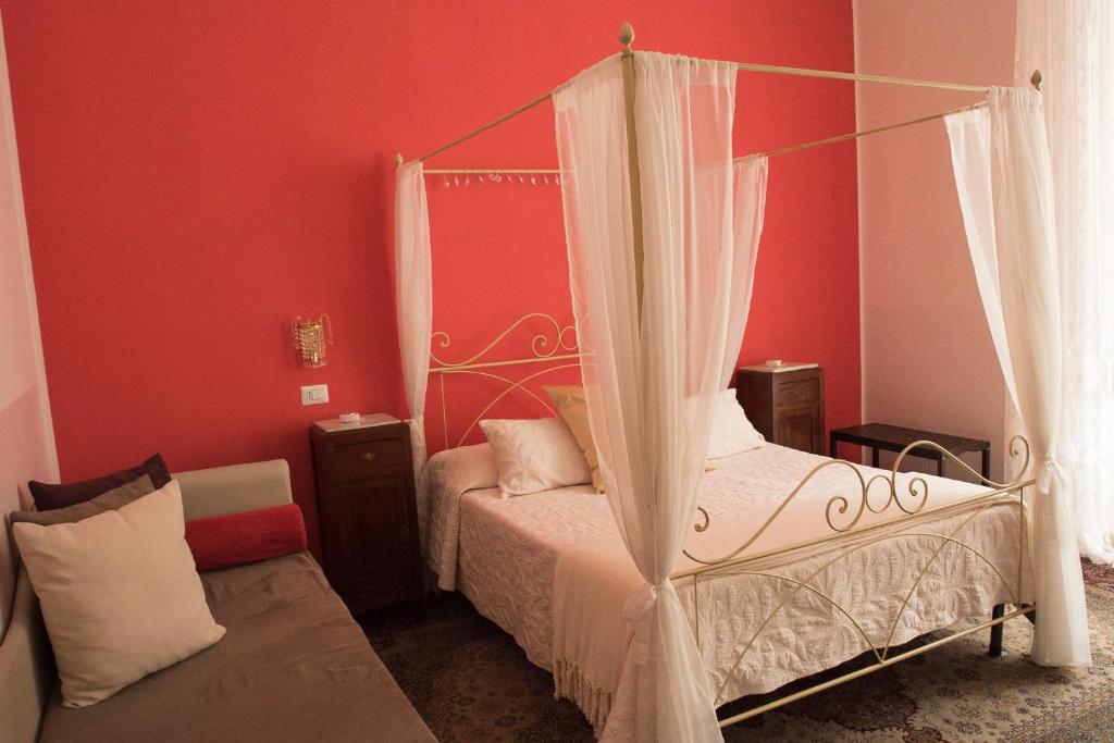 サレルノにあるB&B Domus Garibaldiのベッドルーム(天蓋付きベッド1台、ソファ付)