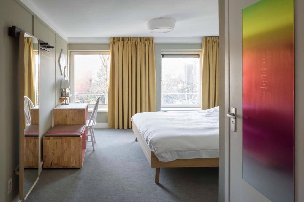 a bedroom with a bed and a desk and a window at Hotel Light in Rotterdam
