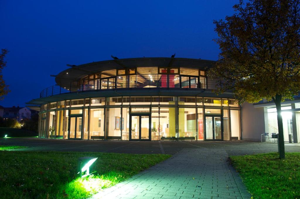 un grand bâtiment avec des fenêtres en verre la nuit dans l'établissement GenoHotel Baunatal, à Baunatal