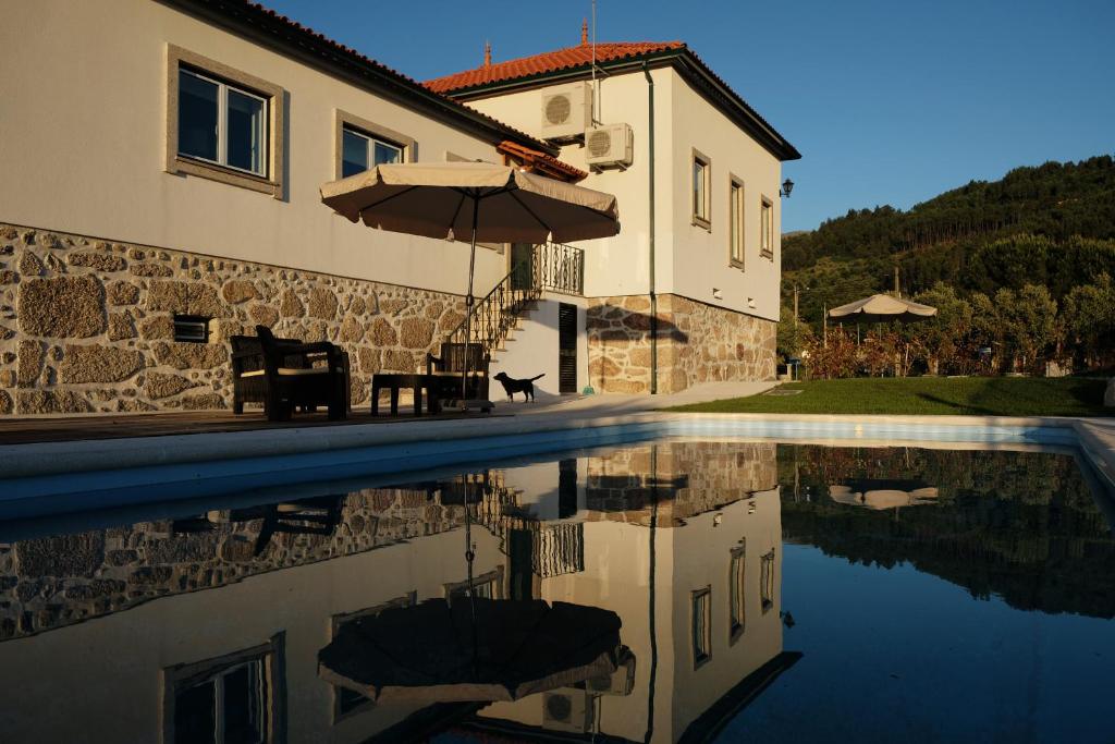 a house and a swimming pool with an umbrella at Quinta de Vodra in Seia