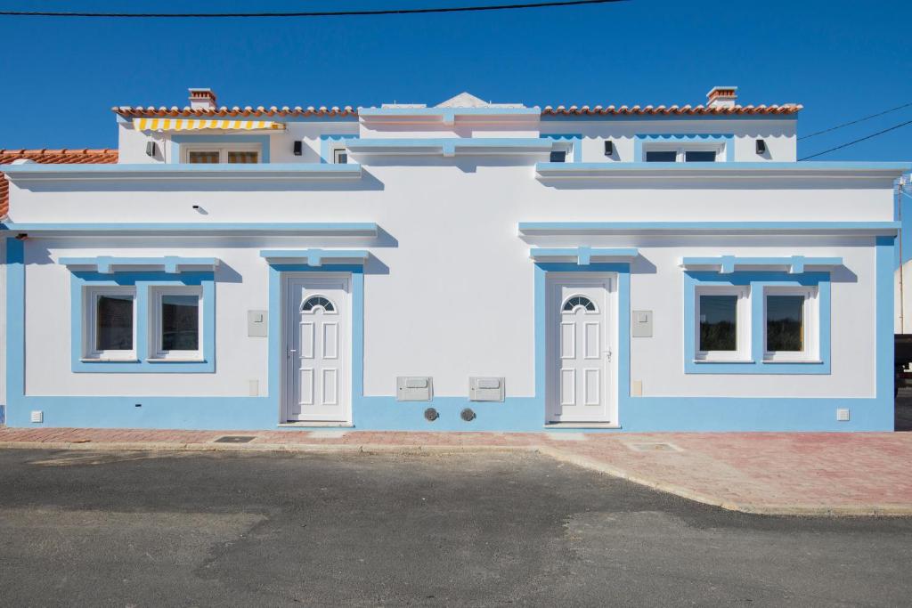 un edificio bianco con finiture blu su una strada di Cavaleiro Rota Costa Alentejana a Cavaleiro