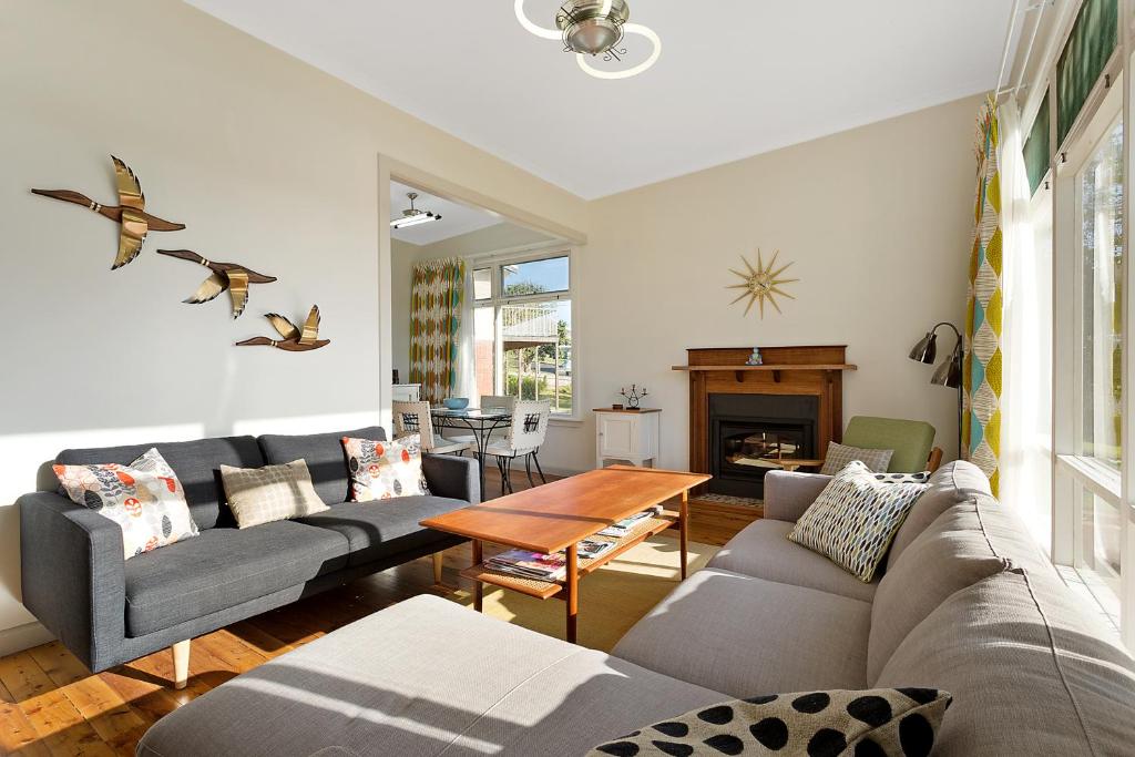 uma sala de estar com um sofá e uma mesa em The 50's Beach House em Merimbula