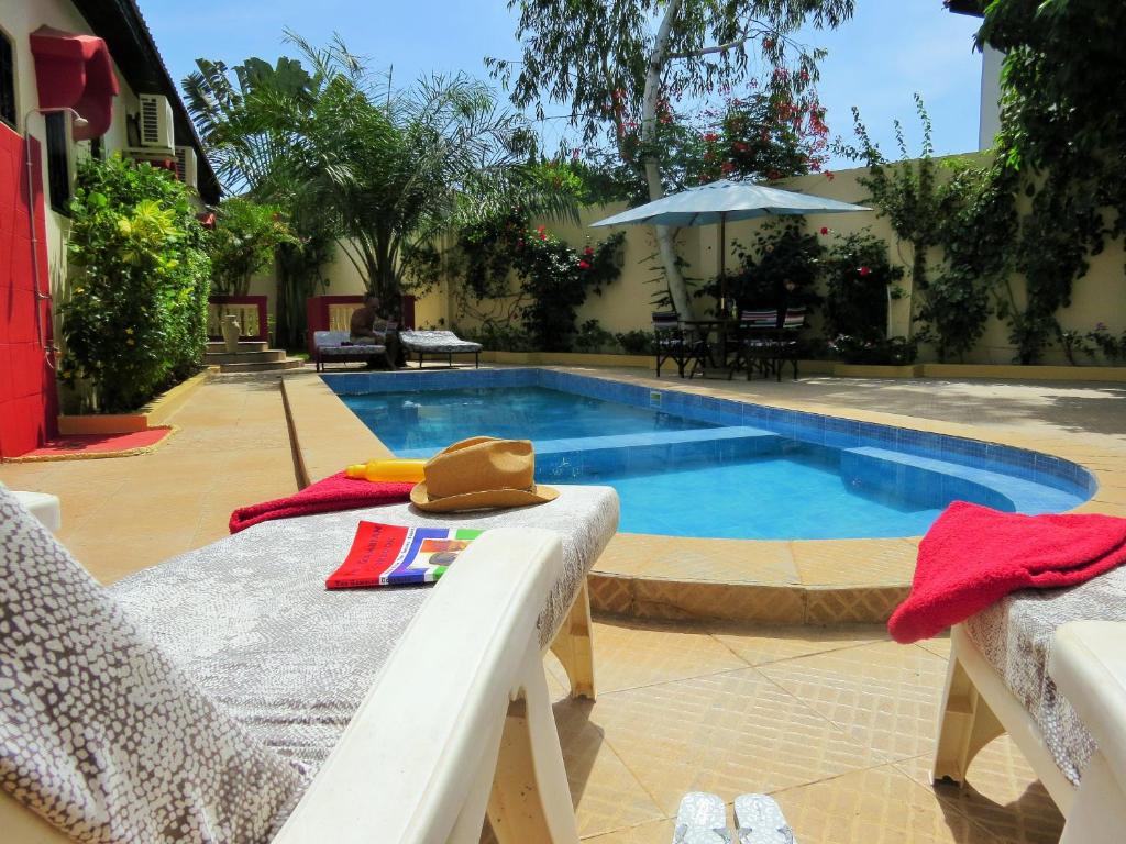een zwembad met een hoed op een tafel ernaast bij Kingfishers Apartments in Bijilo