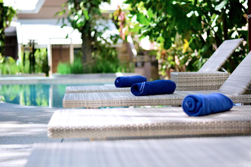 a row of chaise lounges with blue rolled up towels on them at Deevana Krabi Resort in Ao Nang Beach