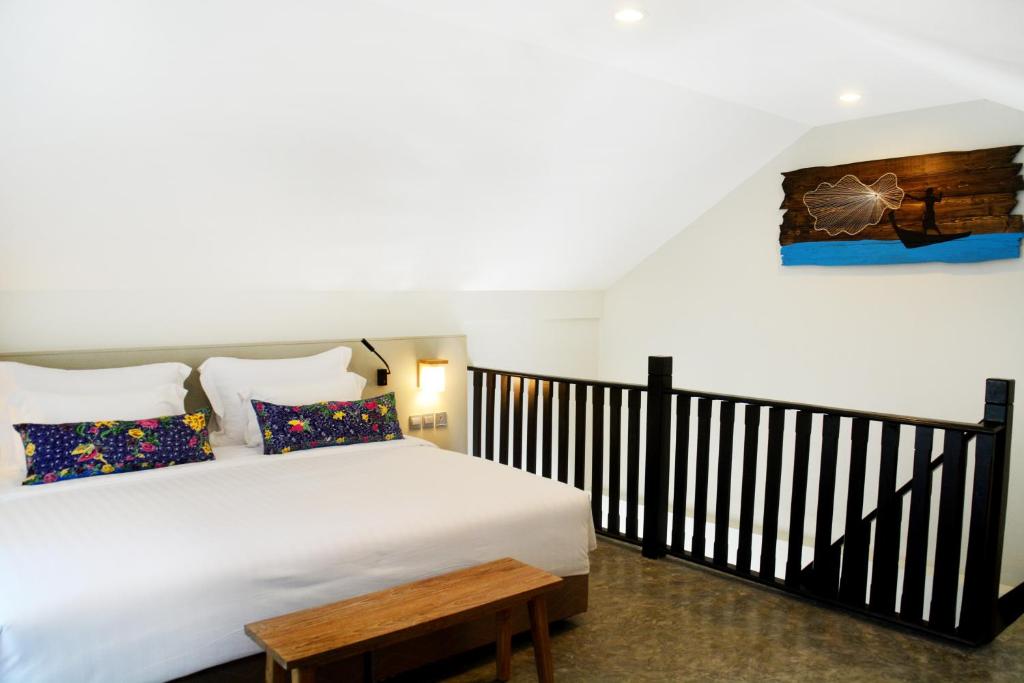 a bedroom with a white bed with a wooden bench at Deevana Krabi Resort in Ao Nang Beach