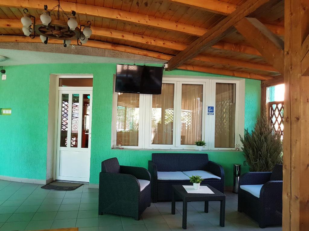 a living room with chairs and a tv on a green wall at Pensiunea Verde in Cluj-Napoca