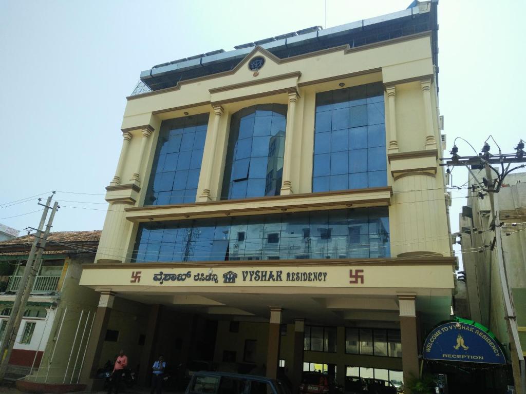 a building with a sign on the front of it at Hotel Vyshak residency in Mysore