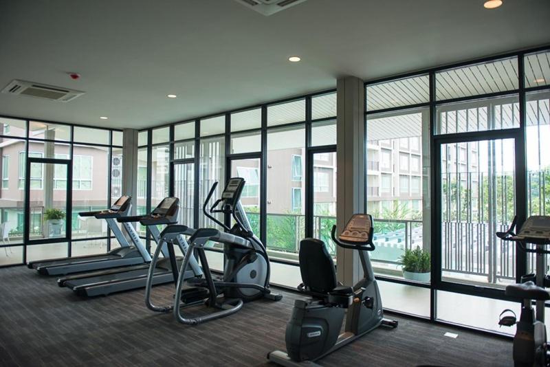 a gym with several treadmills and ellipticals and windows at Baan Peang Ploen Condonium by Yongwisut in Hua Hin