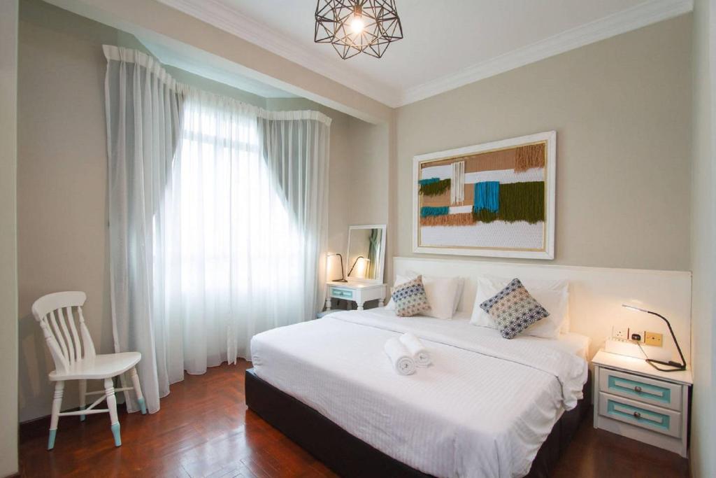 a bedroom with a white bed and a white chair at Century Bay Private Residences in Bayan Lepas