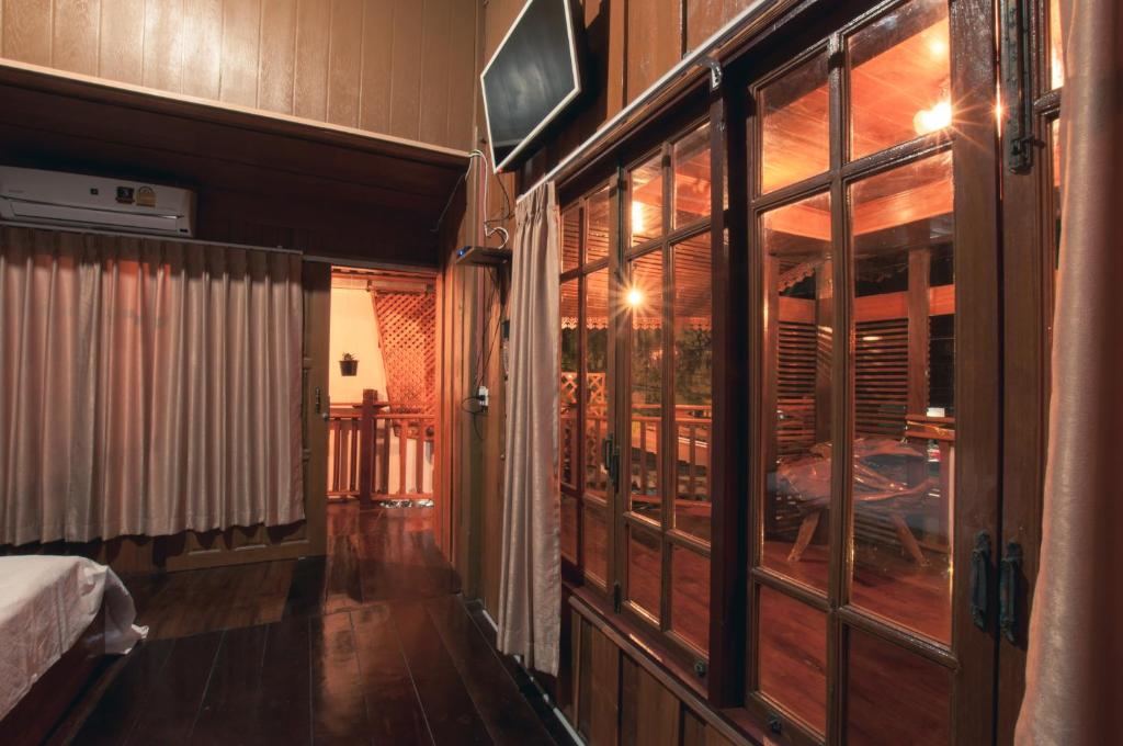 a room with a bed and a room with windows at The history cafe' & guesthouse in Sukhothai