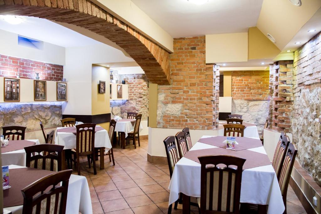 a restaurant with tables and chairs and a brick wall at Hotel Maksymilian in Krakow