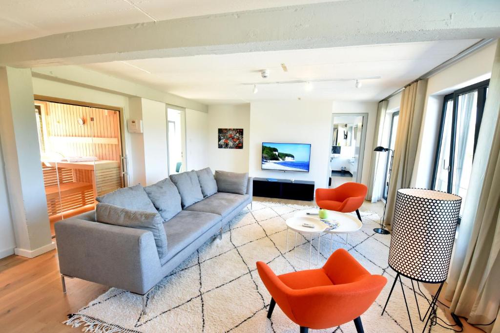 a living room with a couch and orange chairs at Prora Düne 7 in Binz