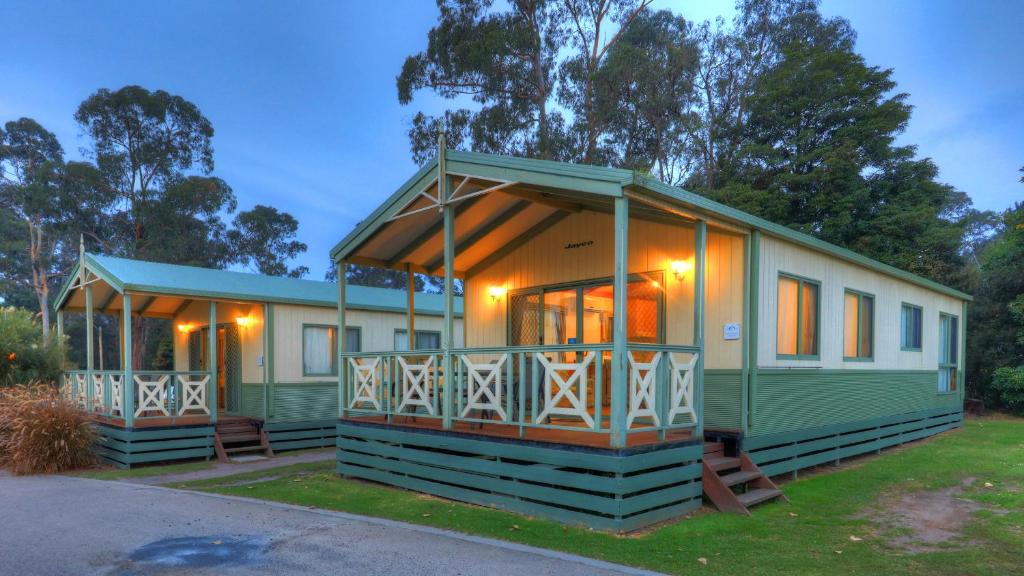 ein modulares Haus in Grün und Weiß mit einer Veranda in der Unterkunft Eden Gateway Holiday Park in Eden