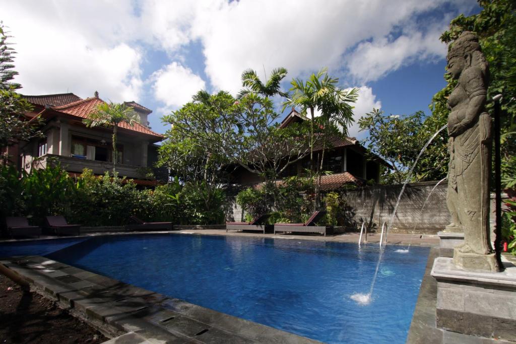 a swimming pool in front of a house with a fountain at Ubud Terrace in Ubud